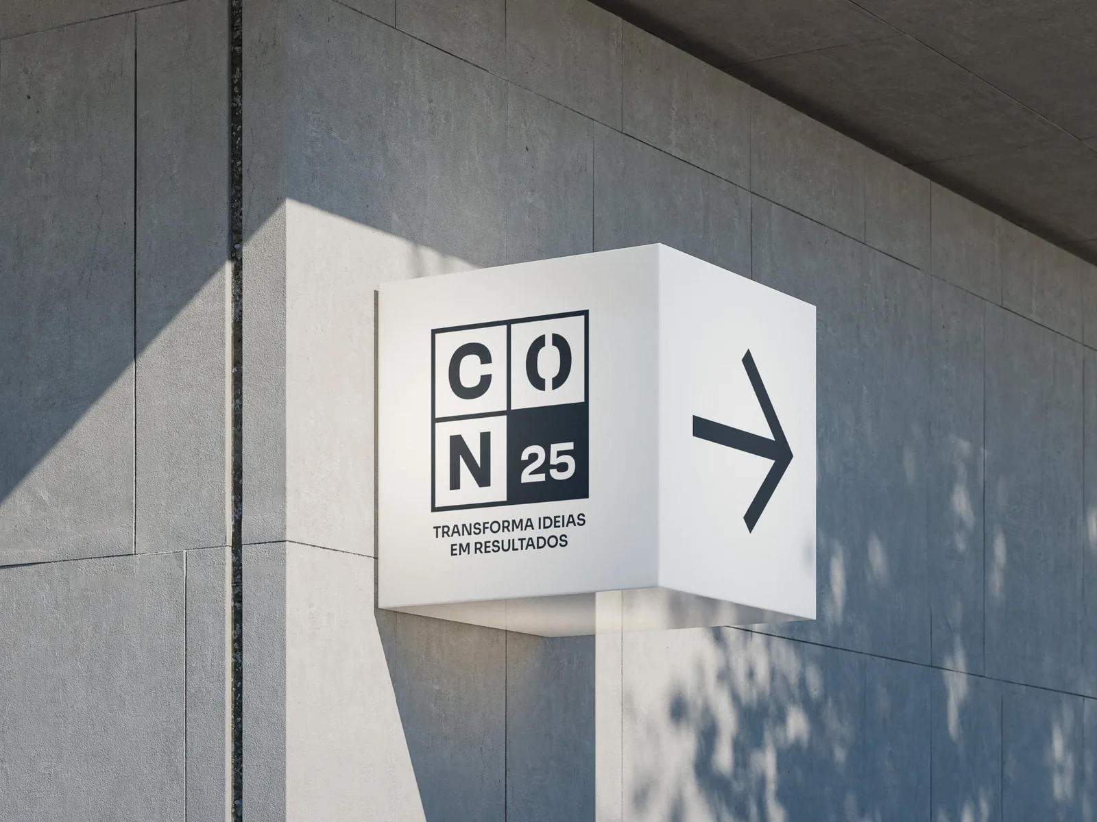 A Connect 25 wayfinding cube on a concrete wall: the four-cell CON 25 logo, the line Transforma ideias em resultados and an arrow